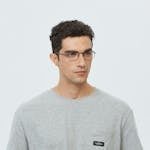 Portrait of a young man wearing glasses and a gray T-shirt in a studio setting.